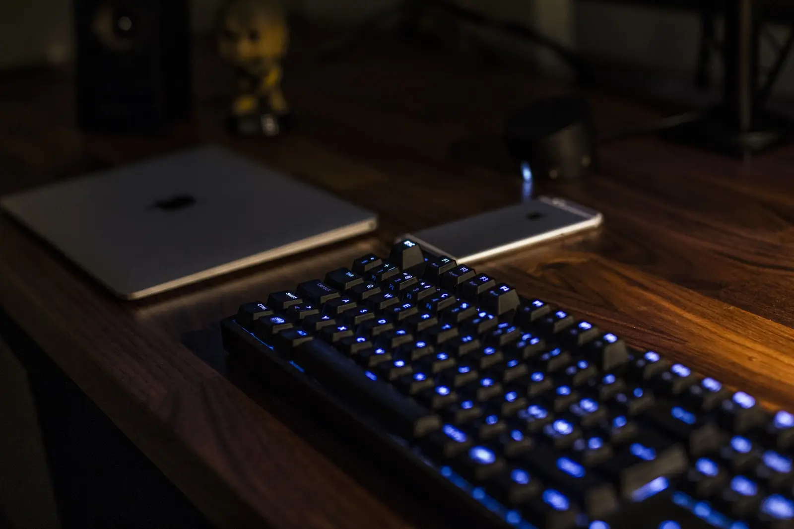 Podświetlana klawiatura w ciemności obok laptopa i smartfona